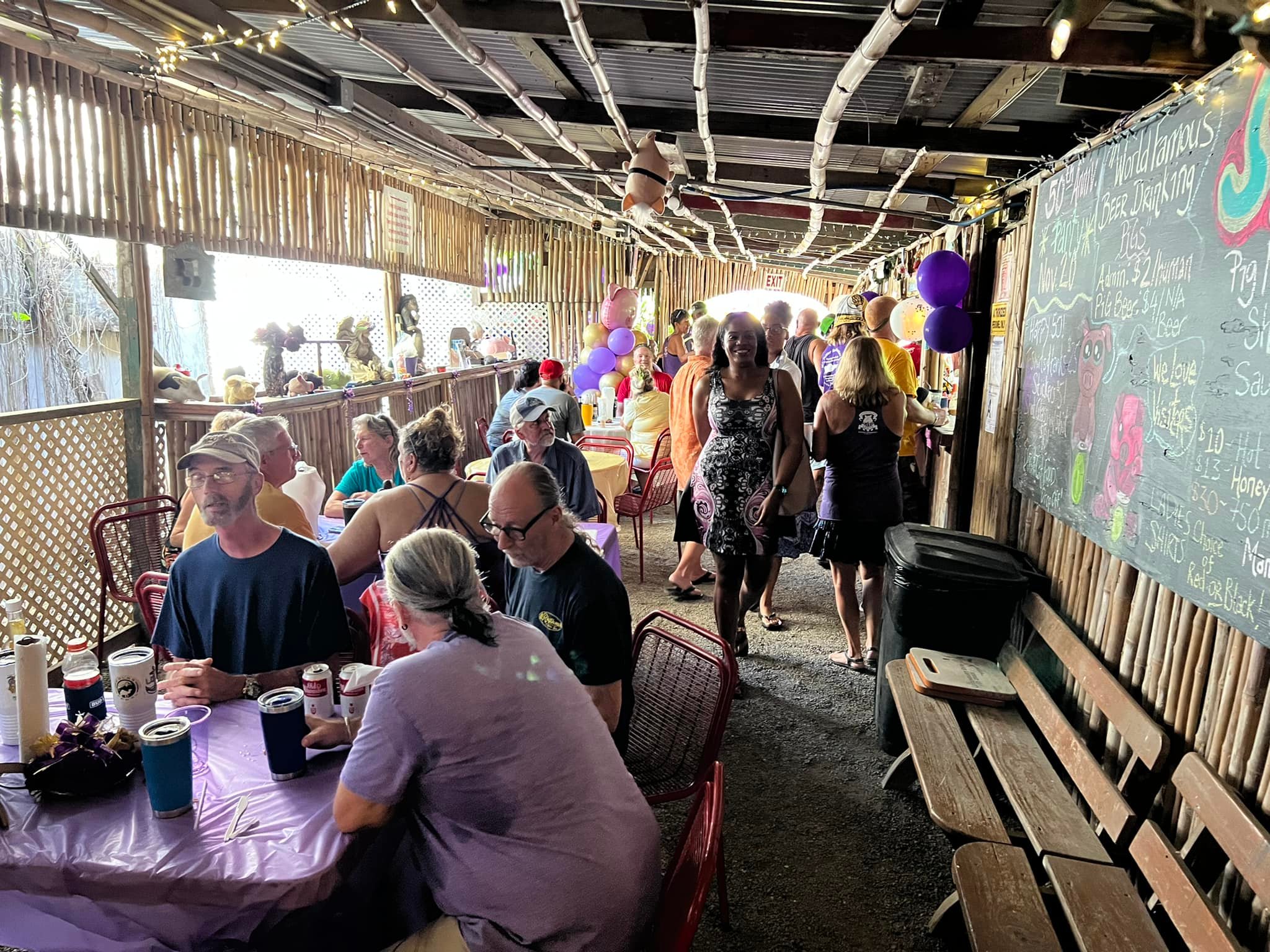 The Domino Club interior during a busy event with purple tablecloths, red chairs, bamboo walls, and string lights