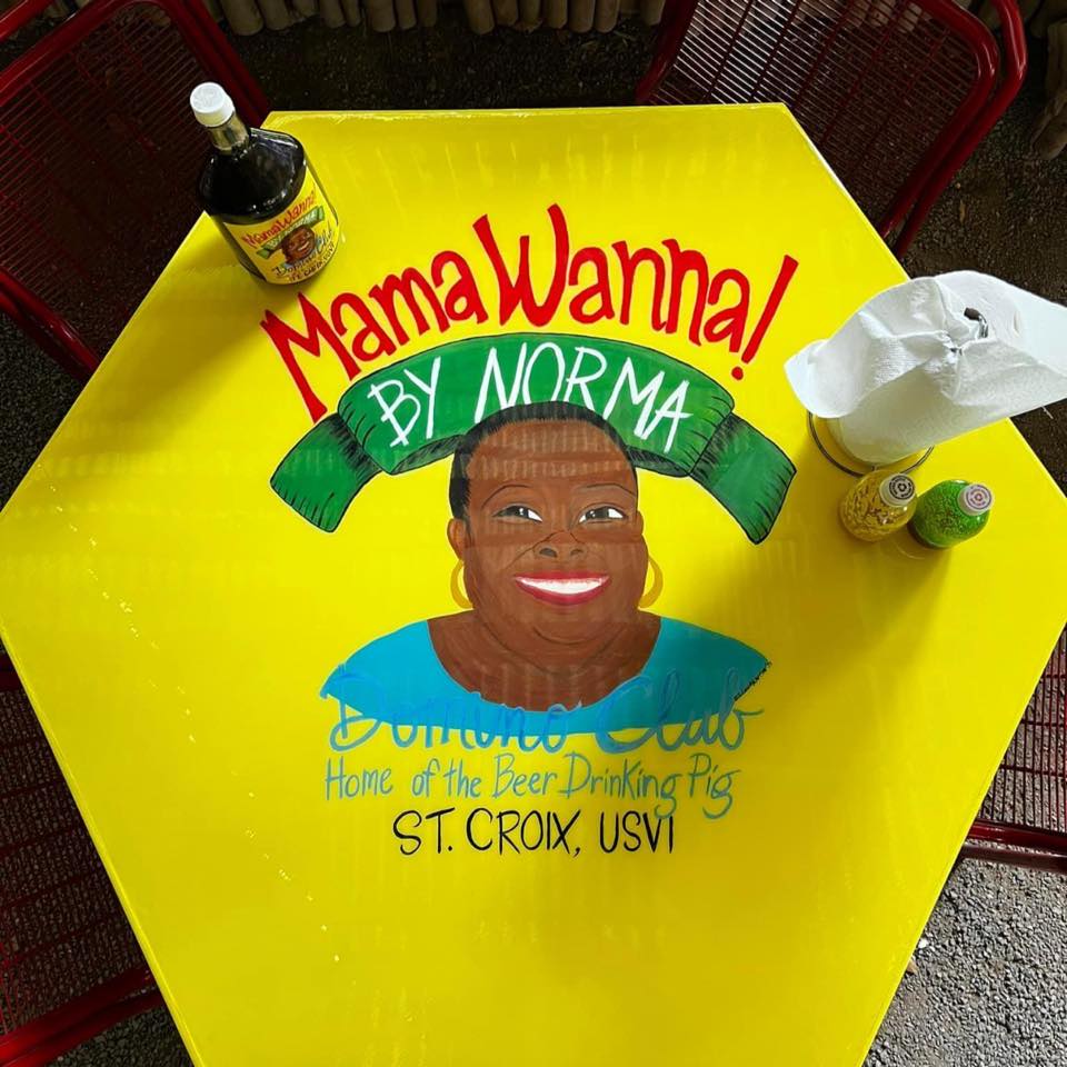 Bright yellow hexagonal table painted with Norma's portrait and 'MamaWanna by Norma, Domino Club, Home of the Beer Drinking Pig'