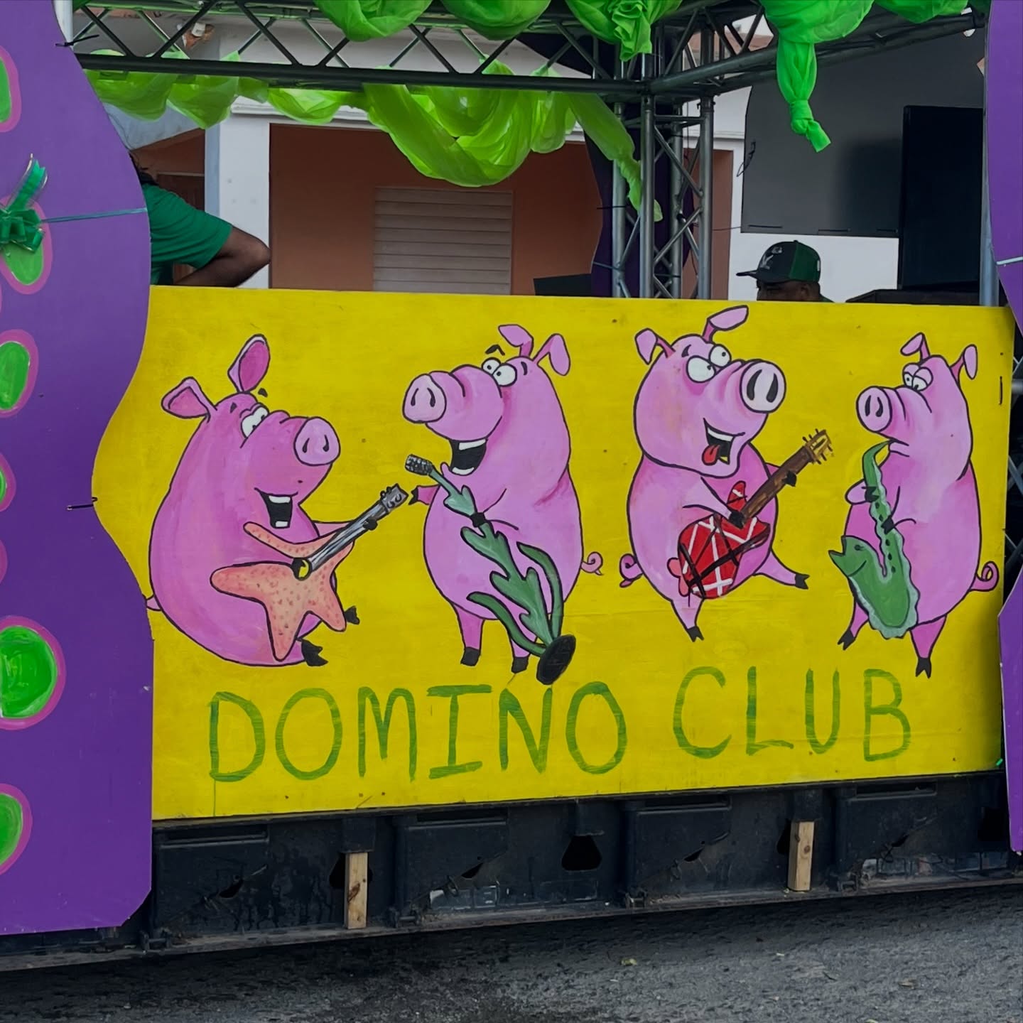Parade float panel with cartoon pigs playing musical instruments on a bright yellow background
