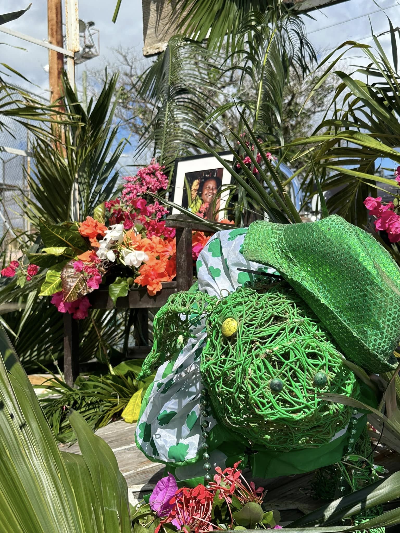 St. Patrick's Day memorial arrangement with flowers, shamrock decorations, and a framed tribute photo